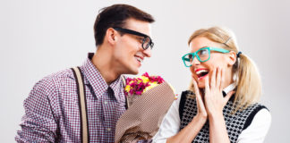 Two cute young adults laughing and holding flowers