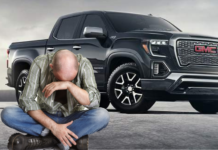 Black 2019 GMC Sierra 2500HD behind man wallowing in sadness
