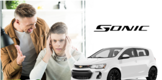 Man lecturing teenage son, white 2019 Chevy Sonic to side