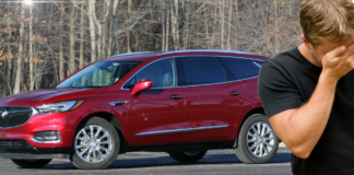 A man with his face in his hand in front of a red Buick SUV