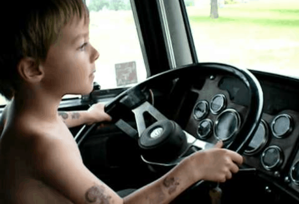 Muddy boy behind a truck steering wheel