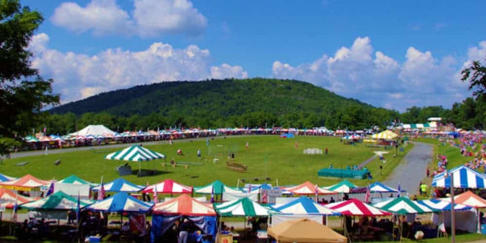 A filed with pop up tents and games is shown with a hill in the background.