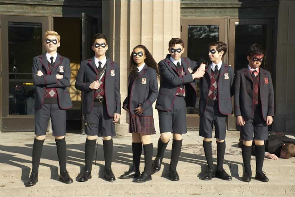 Six kids with private school uniforms are shown wearing superhero masks.