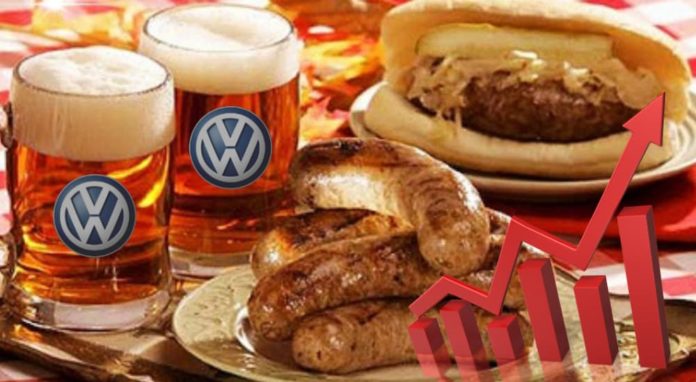Two beer mugs with VW on them are next to sausages and other German food.