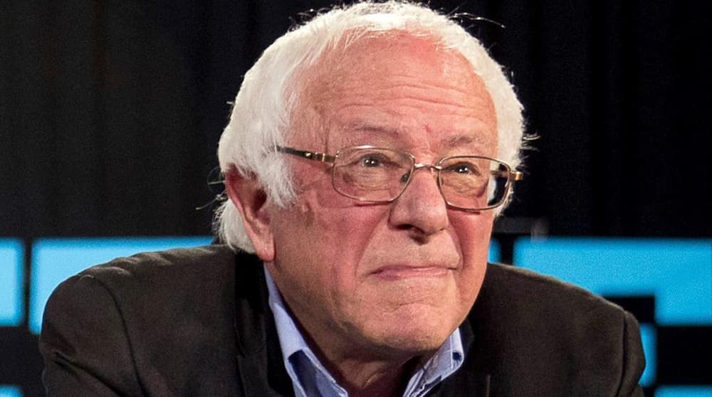 A closeup of Bernie Sanders making an odd face is shown because of his involvement in live auto news.