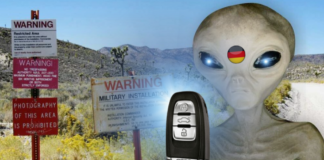 An alien, marked with the German flag, stands outside Area 51, levitating the keys to an Audi