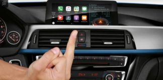 A hand is flipping off the BMW Apple CarPlay feature which is a topic in live auto news.