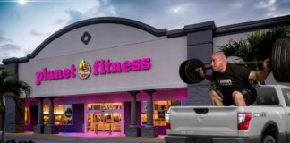A man is lifting weights is in the bed of a truck that is popular among diesel trucks for sale, outside of Planet Fitness