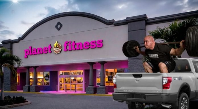 A man is lifting weights is in the bed of a truck that is popular among diesel trucks for sale, outside of Planet Fitness