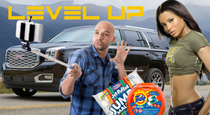 A GMC SUV is parked with Ciara, Level Up, Tide Pods, marshmallows, and a man with a selfie-stick in front of it.