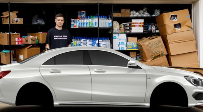 A man is standing behind a white car with his boxes of cleaning supplies.