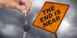 A hand is holding keys in front of a sign that says 'The End is Near.'