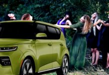 A green 2021 Kia Soul EV is parked in front of modern witches dancing.