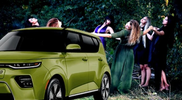 A green 2021 Kia Soul EV is parked in front of modern witches dancing.