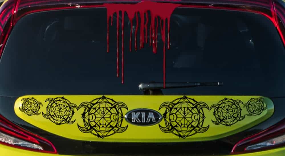 The back of a green 2021 Kia Soul EV has blood and Satanic badging on it.