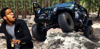 A man is running from a black Jeep Wrangler that is off-roading over rocks.