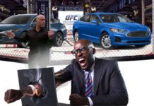 A man is punching through a computer in front of Joe Rogan and a UFC octagon showing a fight between a blue 2020 Chevy Malibu vs 2020 Ford Fusion.
