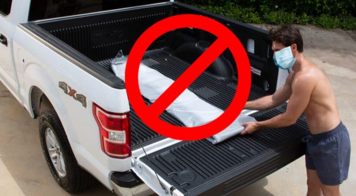 A crossed out circle is over a man putting a pool liner in his white truck's bed.