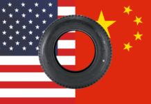 A tire is in front of half an American flag and half a Chinese flag.