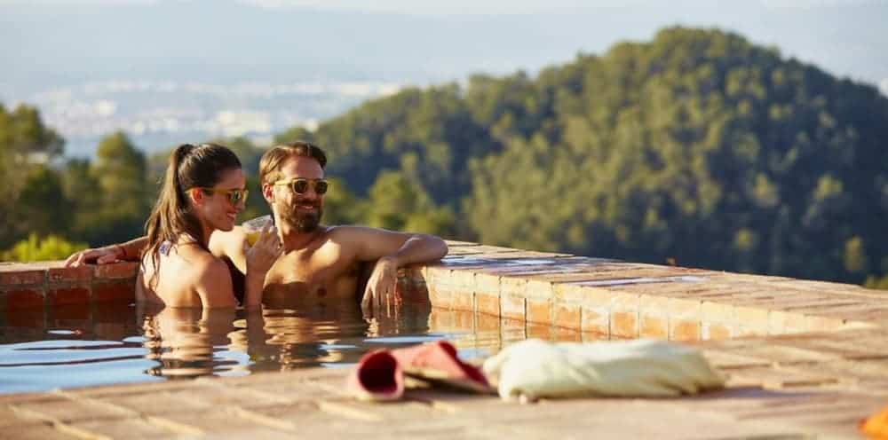 A man and woman are in a pool with a nice view.
