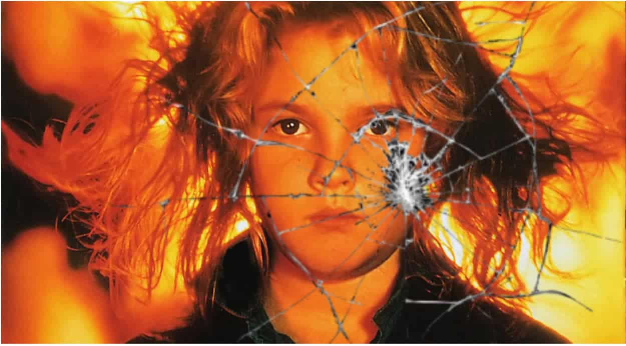 Child Carrie is in front of fire and behind broken glass.