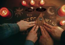 Hands are on a ouija board that has the Ford and Chevy logos on it.