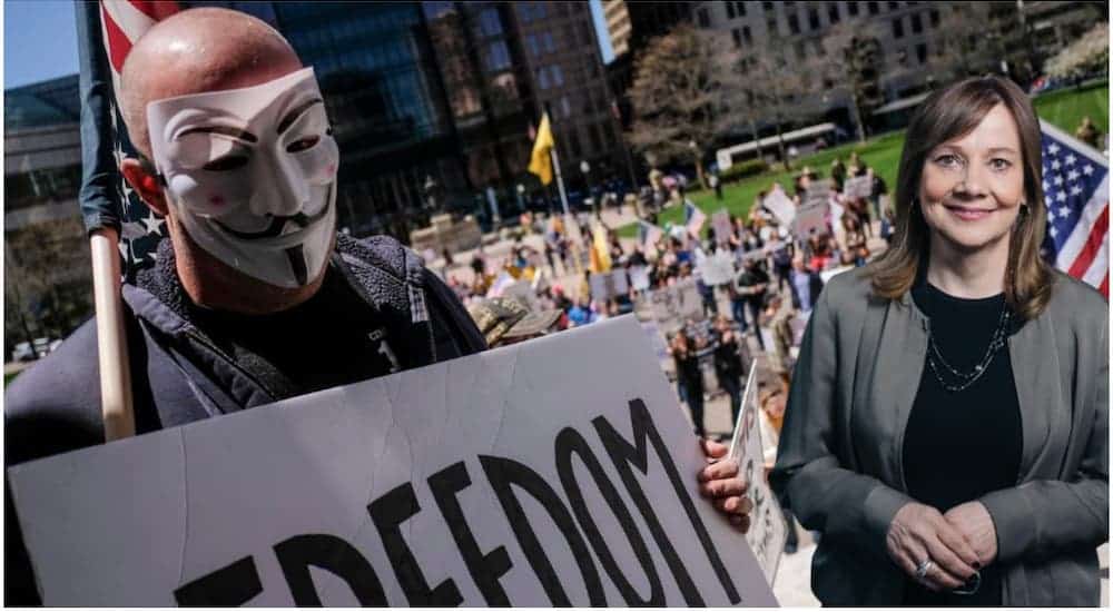 A protestor with a Guy Fawkes mask and sign that reads 'freedom' is protesting outside a government building.