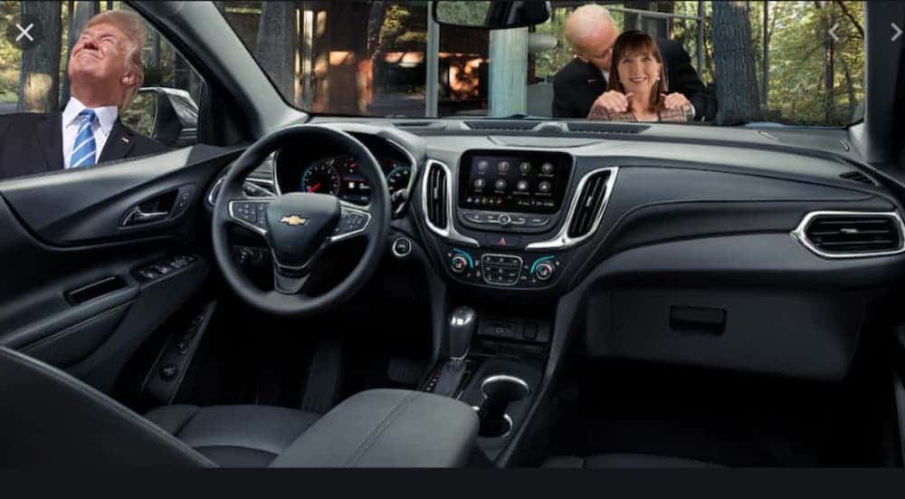 The interior of a 2020 Chevy Equinox is shown with Donald Trump staring at the sun in one window and Joe Biden sniffing a woman in another.