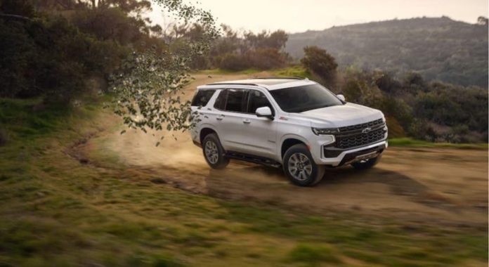 A white 2021 Chevy Tahoe is driving on a dirt road and spitting murder hornets and somehow has something to do with a 2020 Chevy Equinox vs 2020 Hyundai Santa Fe comparison.