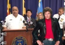 A group of people including Elon Musk and Michael Knight are at a podium discussing live auto news at a police press conference.