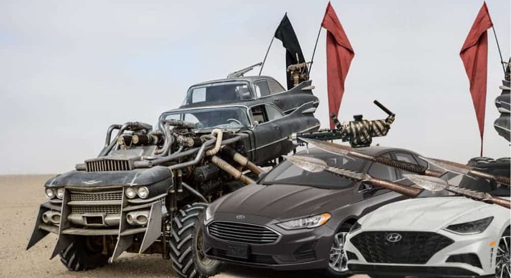 A gray 2020 Ford Fusion, a white 2020 Hyundai Sonata and a marauder's vehicle are outfitted with weapons in a desert.