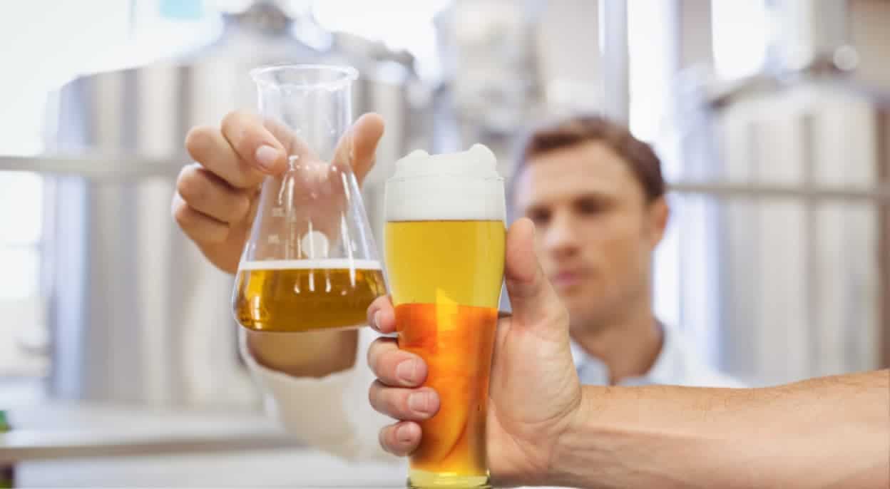 Two men are toasting a beaker and glass of beer.