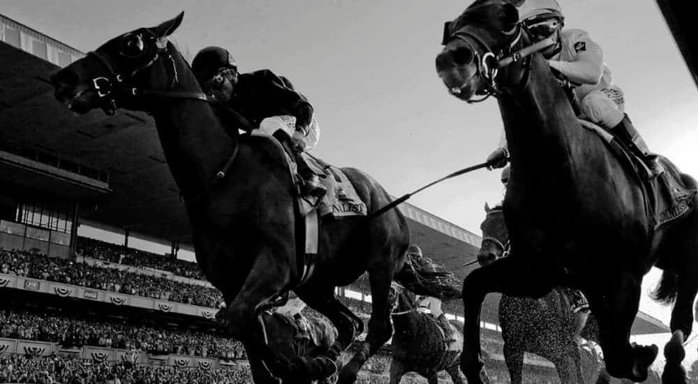 A black in white photo of a horse race.