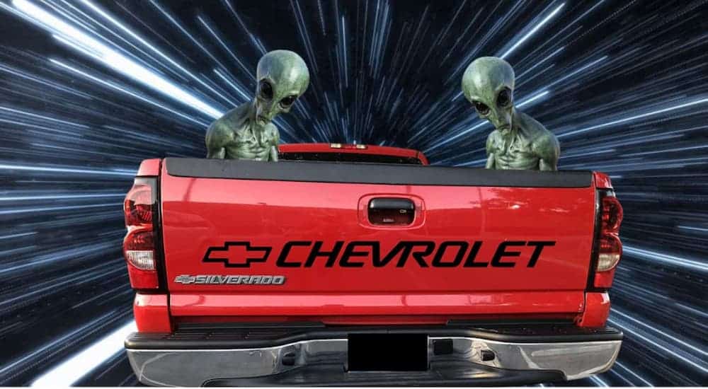 Two aliens are shown in the bed of a red Silverado from a Chevy Dealership Near you and traveling through hyperspace.