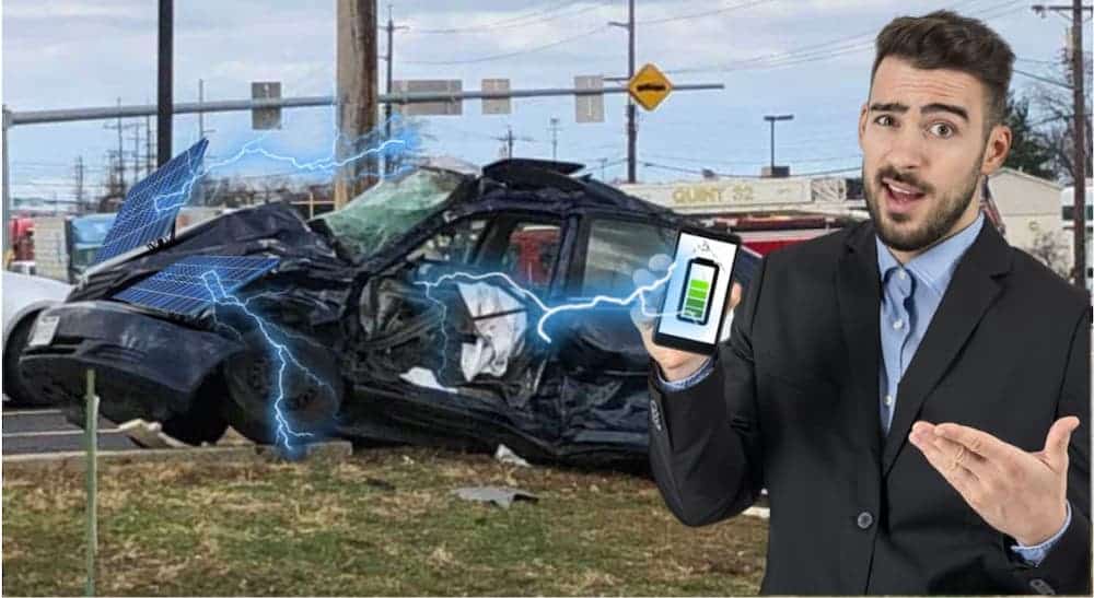 A man his holding a cell phone that is being charged by the car crash behind it.
