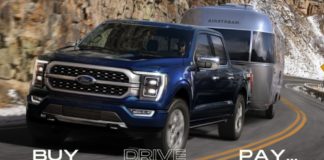 A blue 2021 Ford F-150 is towing an airstream trailer down the highway after leaving a Ford diesel truck dealer.
