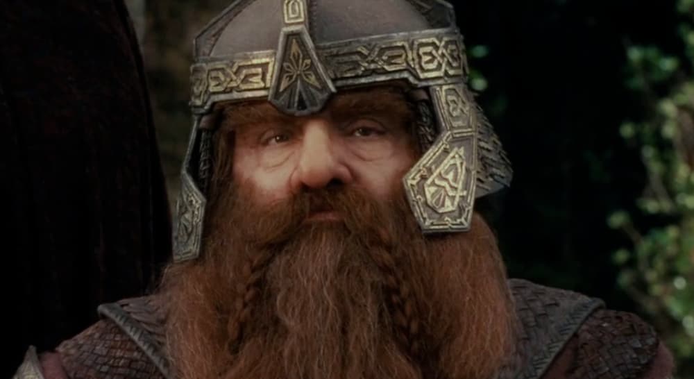 A dwarf named Gimli is wearing a metal hemet.