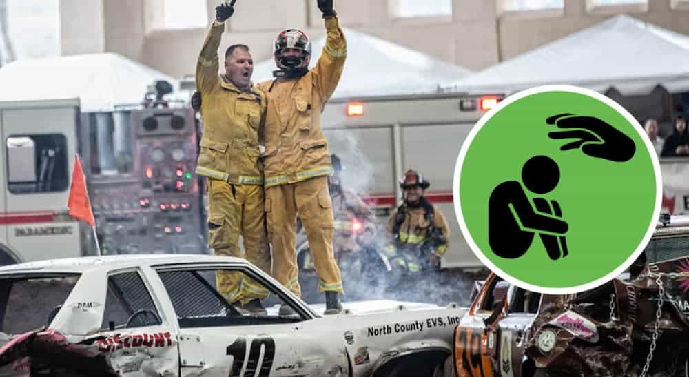 Two firemen are standing on a wrecked car with a green icon next to them that has a sad figure on it.