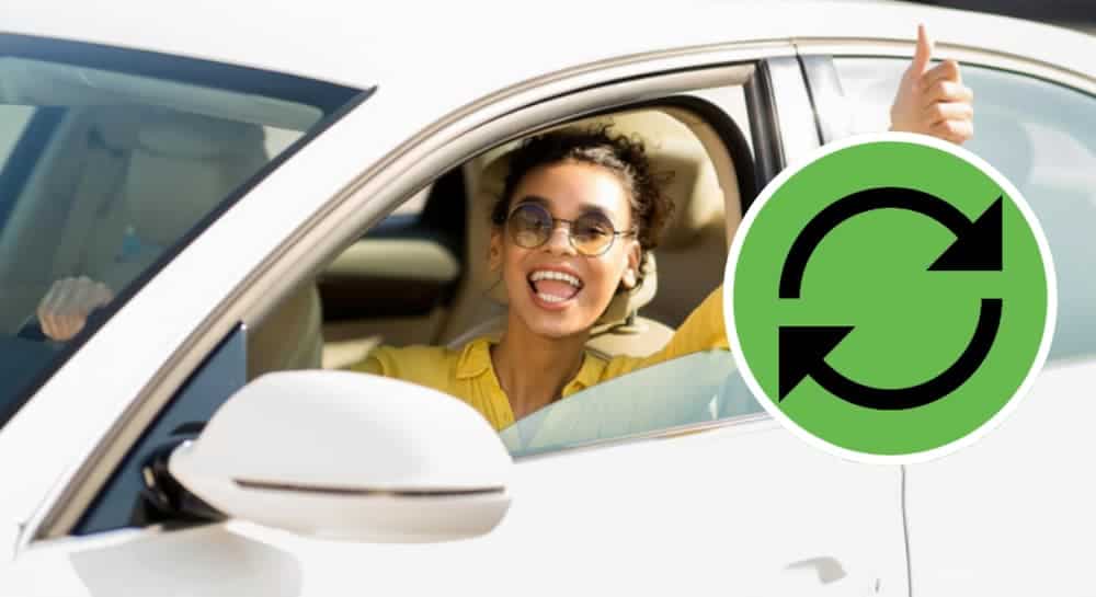 A woman is in a car with a green icon with arrows going in a circle.