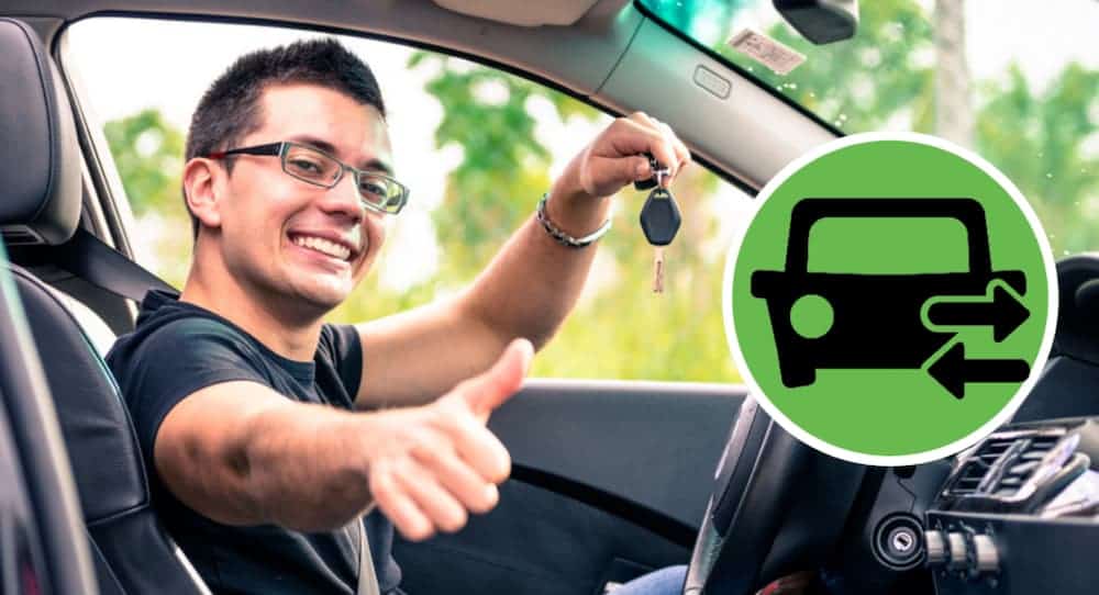 A man inside a car is giving a thumbs up with a green icon next to him.