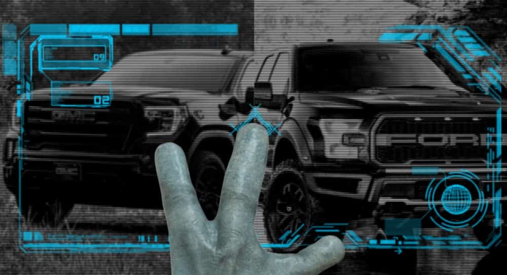 An alien hand is in front of a screen comparing the 2021 GMC Sierra 1500 vs 2021 Ford F-150 in black and white.