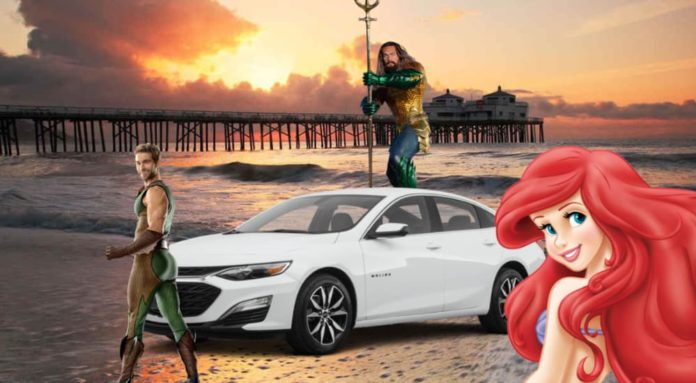 A white 2021 Chevy Malibu is shown on the beach next to Ariel, The Deep, and Aquaman.