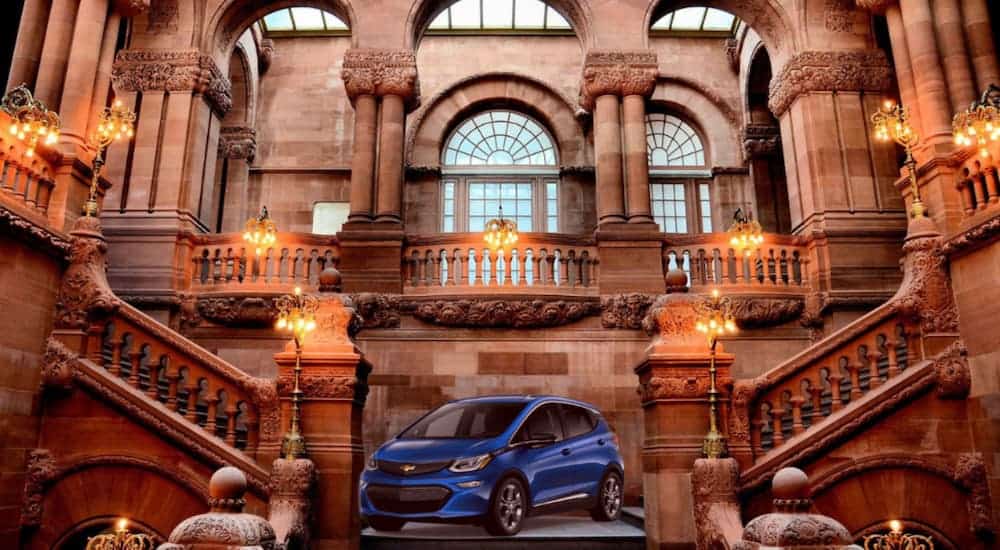 A blue 2021 Chevy Bolt EV is parked at the bottom of a staircase after leaving an Albany car dealership.
