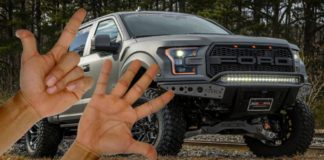 A hand holding up two fingers and a hand holing up five are shown in front of a dark grey 2021 Ford F-150 Raptor.