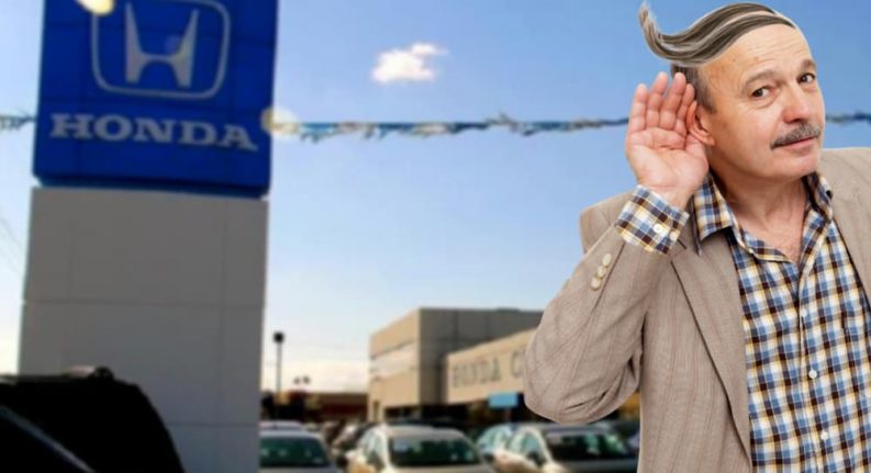 Mark Bobkins has his hand to his ear in front of a Honda dealership sign.