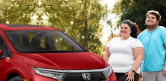 A couple is standing next to a red 2022 Honda Odyssey.