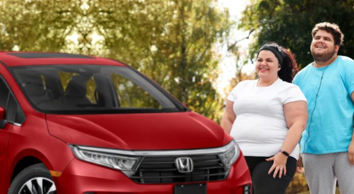 A couple is standing next to a red 2022 Honda Odyssey.