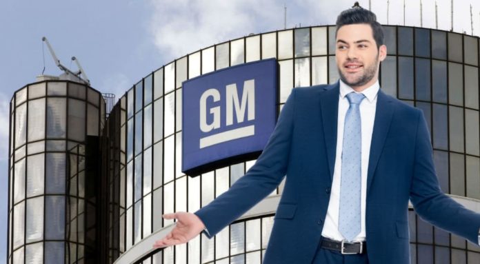 A man in a suit and tie is standing in front of the GM building holding his hands out.