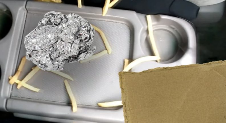 Tin foil and fries are on a vehicle's center console.