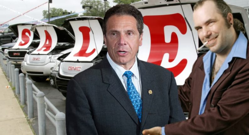 Andrew Cuomo and a salesman are in front of a line of GMCs with a 'SALE' sign.
